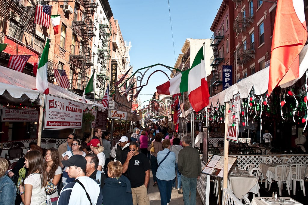 Rue animée avec décorations italiennes et foule dense.