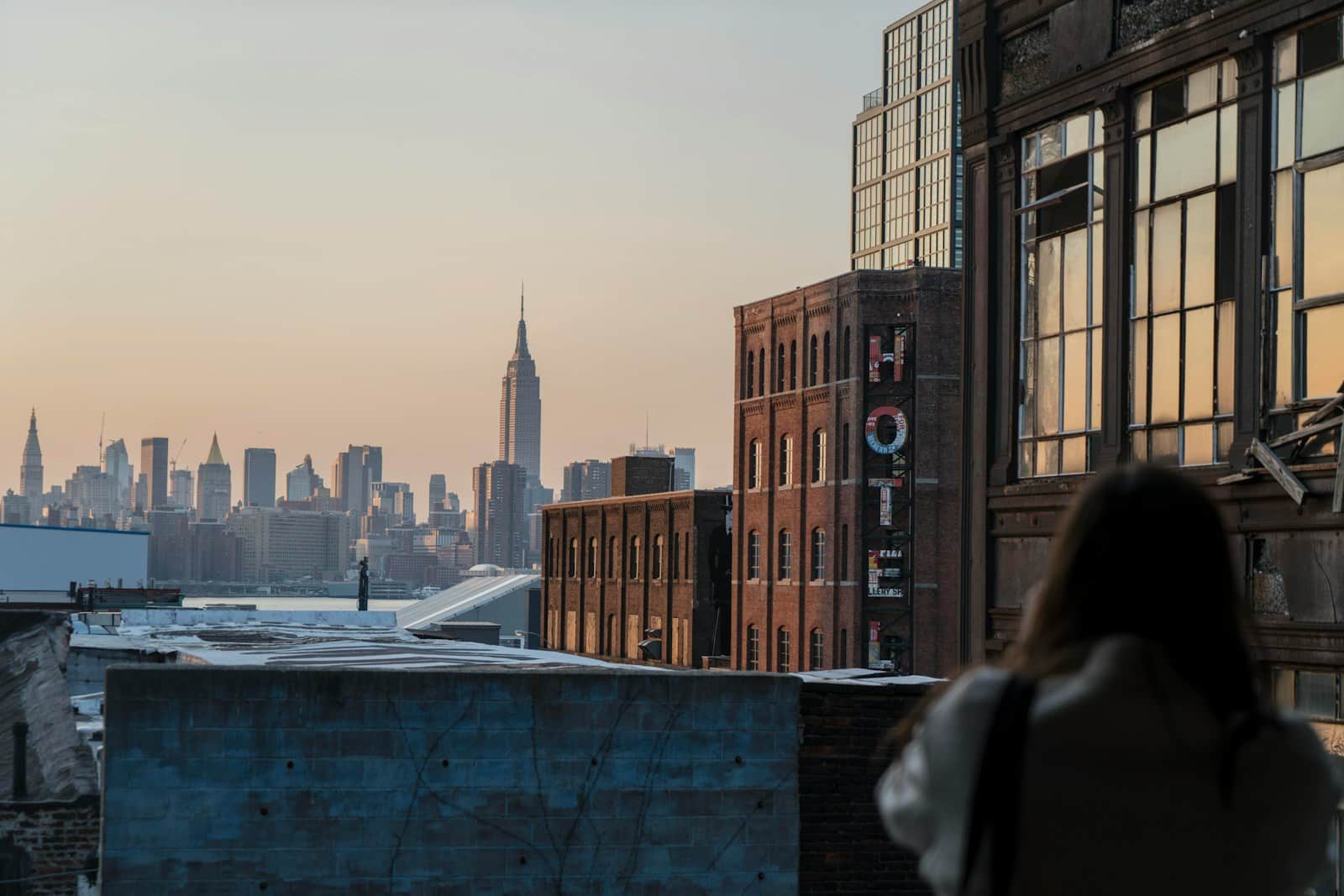 Femme observant skyline de New York au coucher du soleil.