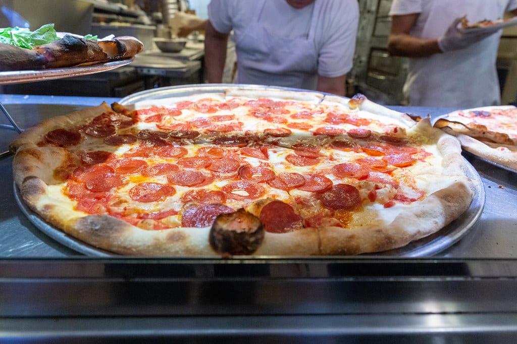 Pizza pepperoni chaude en pizzeria, cuisiniers en arrière-plan.
