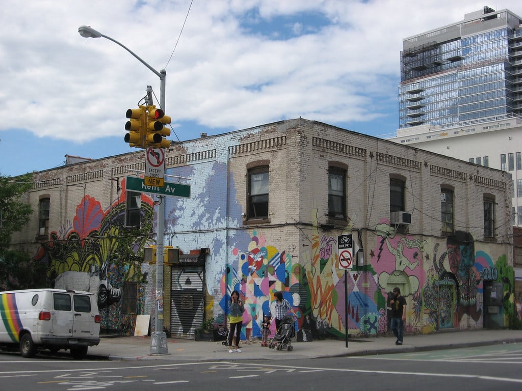 Bâtiment urbain graffité avec personnes et véhicule.