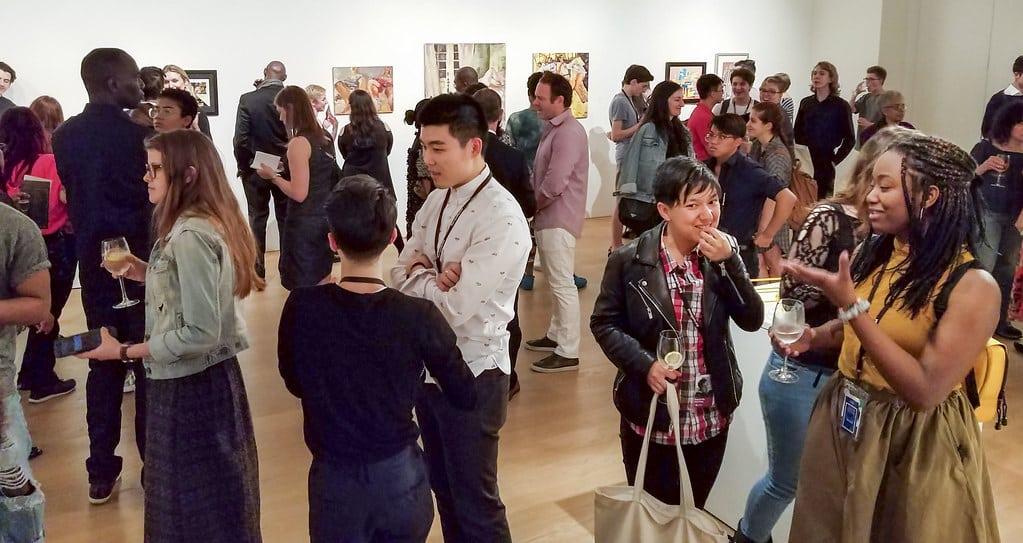 Visiteurs divers lors d'un vernissage dans une galerie d'art.